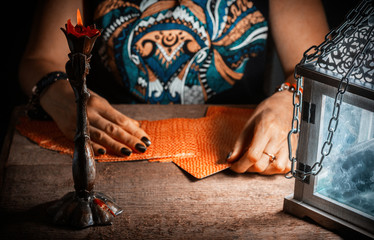 A woman lays out the tarot cards by the light of a lantern and a candle. Selective focus. © vladk213
