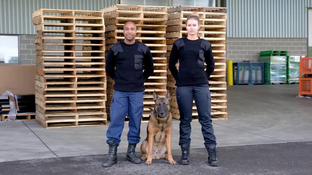 Professional dog handlers on a security detail outside of an industrial building.