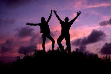 silhouette of a man and a girl on top of the mountain against the evening sky. success, achievement. tourism.