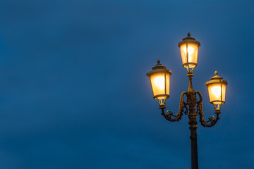 Fototapeta na wymiar Illuminated street lights in Venice against a blue evening sky.