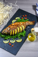 Large baked carp with herbs, lemon and spices. top view, place for text. vertical image