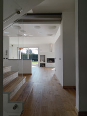 interiors shots of a modern living room in the foreground the wooden staircaseon the background the fireplace the floor is made of wood