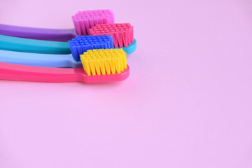 Four colorful toothbrushes blurred on front at the pink background. Toothbrush for personal routine morning  hygiene on neutral blurred backdrop. Dental plastic tool with empty space for image or text