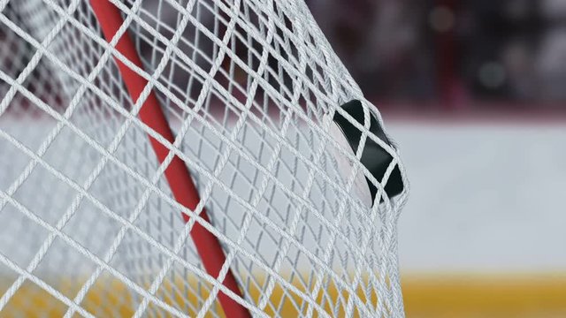 Beautiful Hockey Puck Flies into Goal Net in Slow Motion with Tribunes Background. Close-up Goal Moment. Beautiful 3d animation Sport Concept. 4k Ultra HD 3840x2160.