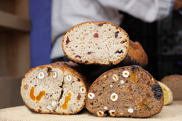 Three breads on a table with nuts, raisins, dried apricots, prunes and cranberries. Side view .