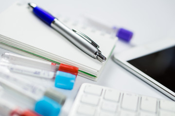 Making notes for samples used in laboratory or medicine hospital, next to computer tablet and computer keyboard on the white background