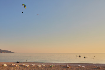 Paraglider silhouette flying over misty mountain valley in beautiful warm sunset colors - sport, active wallpapers full of freedom.