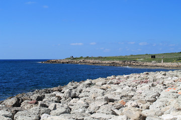 Stony shore of the Mediterranean sea and a promenade on a sunny spring day