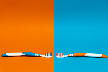 Fototapeta premium Worn / Used and New Toothbrush on a split orange and blue background