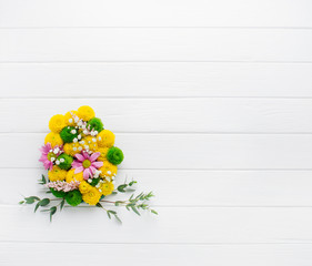 Easter egg made from flowers on white wooden background with copy space