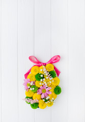 Easter egg made from flowers on white wooden background