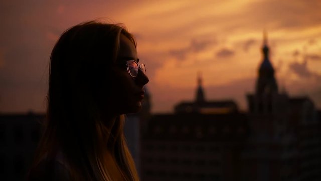 Close up young silhouette woman with glasses stand during sunset relaxing amazing apartment enjoying looking watching home hope future successful skyline luxury back girl shadow slow motion