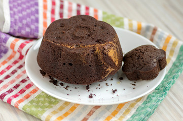 Chocolate cake on white plate on colorful kitchen towel, tasty sweet dark brown biscuit