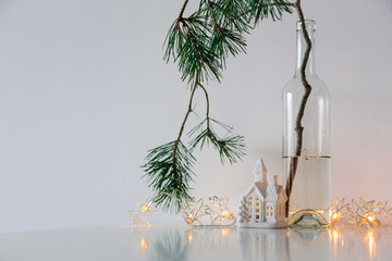 Scandinavian Christmas decor. pine branches, garland and a ceramic house lamp