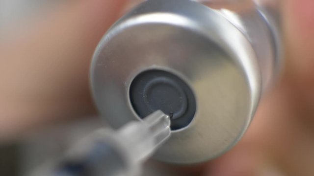 Vaccine in vial with syringe and needle in doctor's hand