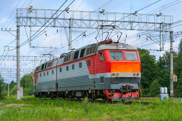 Electric locomotive on the railroad on a background of green trees