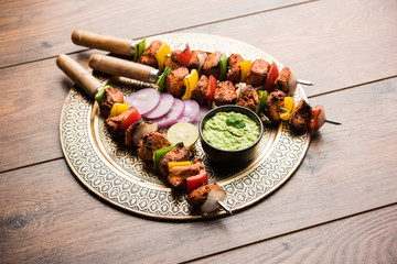 Chicken tikka /skew Kebab. Traditional Indian dish cooked on charcoal and flame, seasoned & colourfully garnished. served with green chutney and salad. selective focus