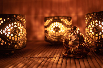 Golden monk figure between three candles on wooden background. - Powered by Adobe
