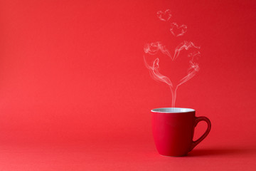 Cup of tea or coffee with steam in one heart shape on red background. Valentine's day celebration or love concept. Copy space