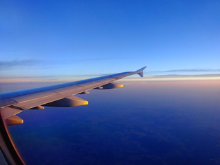 Wing of an Airplane in Sunset during flight into holiday
