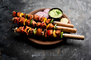 Chicken tikka /skew Kebab. Traditional Indian dish cooked on charcoal and flame, seasoned & colourfully garnished. served with green chutney and salad. selective focus