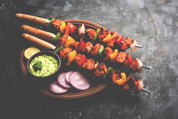Chicken tikka /skew Kebab. Traditional Indian dish cooked on charcoal and flame, seasoned & colourfully garnished. served with green chutney and salad. selective focus