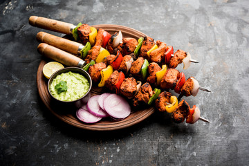 Chicken tikka /skew Kebab. Traditional Indian dish cooked on charcoal and flame, seasoned & colourfully garnished. served with green chutney and salad. selective focus