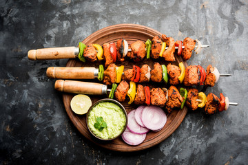 Chicken tikka /skew Kebab. Traditional Indian dish cooked on charcoal and flame, seasoned & colourfully garnished. served with green chutney and salad. selective focus - obrazy, fototapety, plakaty