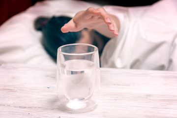 Sleeping woman passing hand to glass of water