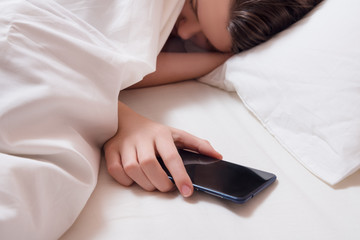 Young girl under the blanket with smart phone in the hand