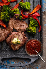 Grilled Beef steak with garlic butter and vegetables. Meat with grilled bell pepper, broccoli and onions.