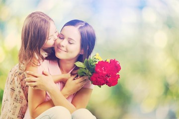 Fototapeta premium Young woman with little girl and beautiful flowers outdoors