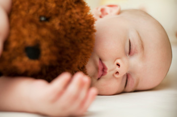 cute little baby sleeping in a sweet sleep hugging a bear