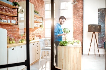 Man cooking healthy food standing on the kitchen of the beautiful loft apartment