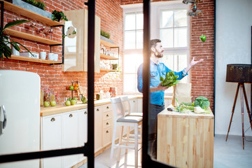 Man cooking healthy food standing on the kitchen of the beautiful loft apartment