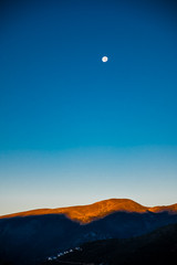 The moon setting as the sun rises over the Alps in France - sunlit peaks of mountains