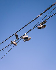 Tennis shoes hanging off of a power line on a busy street with a blue sky background.