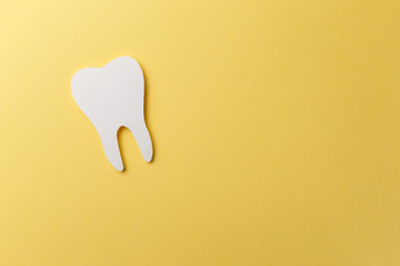 White tooth on yellow background with copy space. Oral dental hygiene. Teeth whitening. Dental...