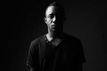 Young African man against black background in black and white