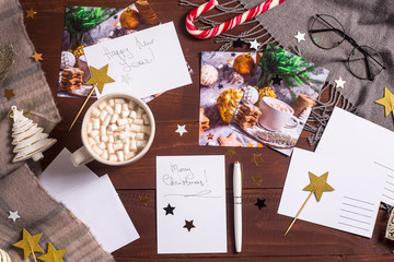 Sign cards for the New Year and Christmas on the table among the decor, stars and a cup of cocoa. Christmas ritual