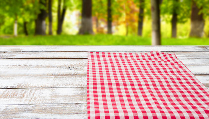 checkered tablecloth on a wooden table on blurred forest background