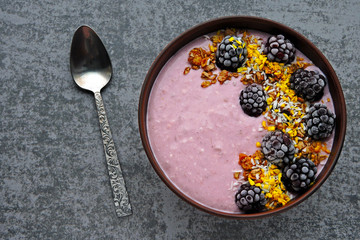 Colorful healthy breakfast bowl with pink yogurt and blackberries.