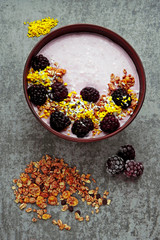 Colorful healthy breakfast bowl with pink yogurt and blackberries.