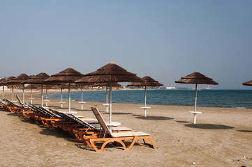 The beach with yellow sand, sun beds and umbrellas. A secluded place. The concept of secluded rest. Cyprus