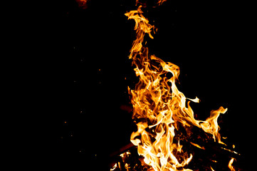 Burning woods with firesparks, flame and smoke. Strange weird odd elemental fiery figures on black background. Coal and ash. Abstract shapes at night. Bonfire outdoor on nature. Strenght of element.