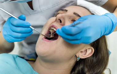 Dentist checking patient's teeth with mirror in dentistry