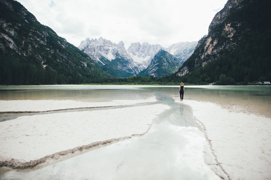 Rear view of woman standing in lake surrounded by mountains