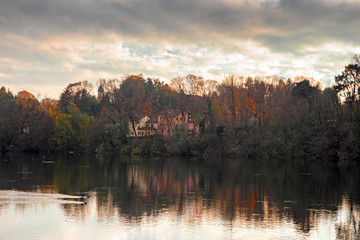 Panoramic view of the Ticino river with clouds and trees that are reflected in its clear water, on a winter day at sunset.