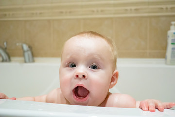 Happy baby looks out of the bath. happy childhood. child care. children's hygiene. water treatments