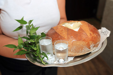 Fototapeta Kelnerka trzyma bochenek chleba z solą, wodą i wódką na przywitanie młodej pary.	 obraz